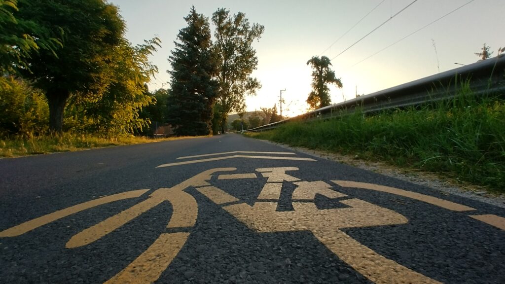 Aszfaltúton sárga biciklis út jel, a háttérben napfelkelte